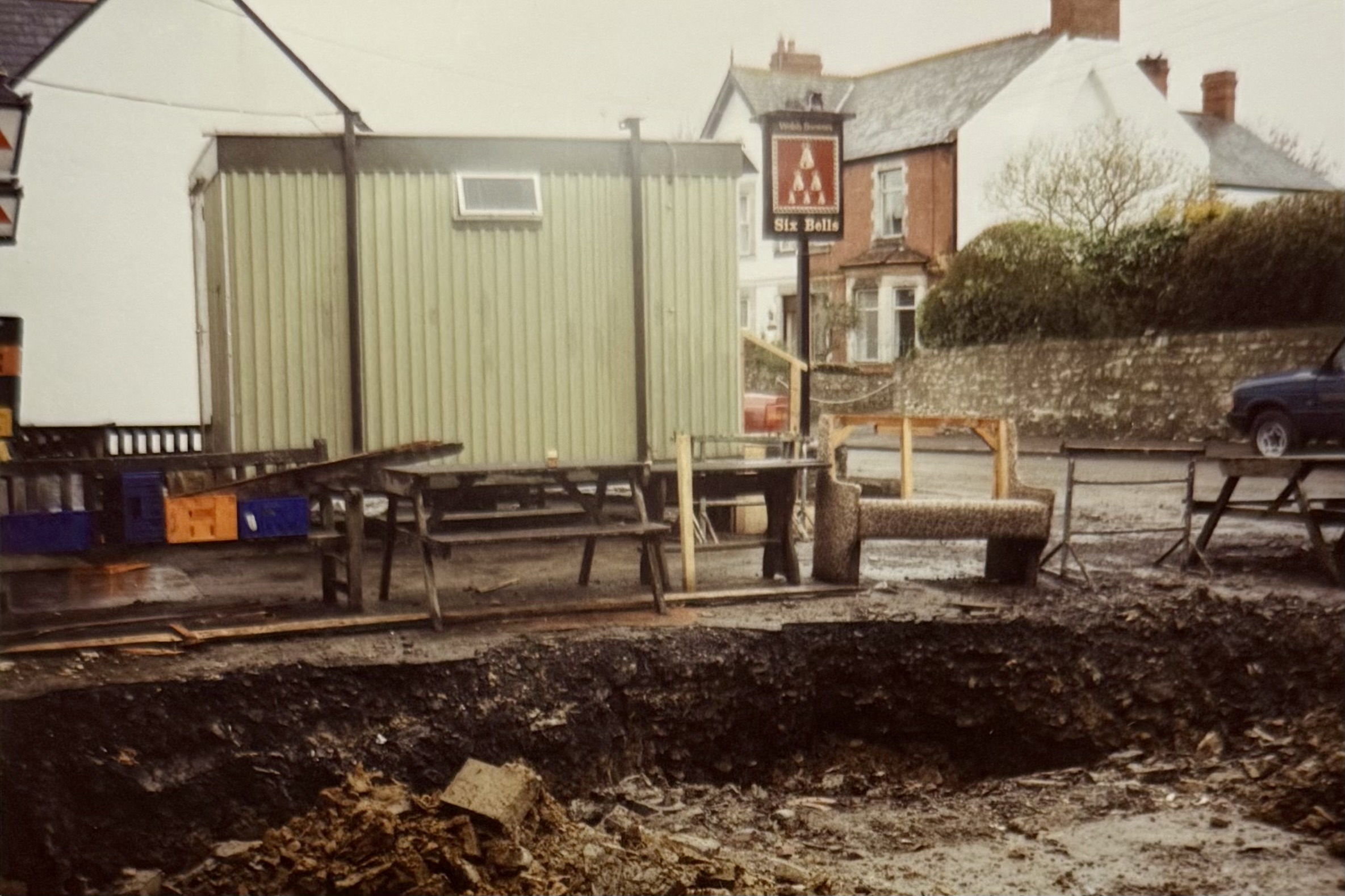 The dug out foundations above from a different angle. A line of benches, picnic tables, and barriers line the area, to stop anyone falling in.