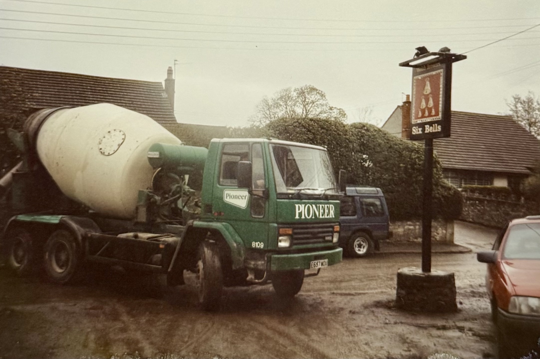 A construction vehicle with Pioneer written on the side, next to the original hanging pub sign. The sign was moved during the renovation, after the wall was constructed around the front of the pub.