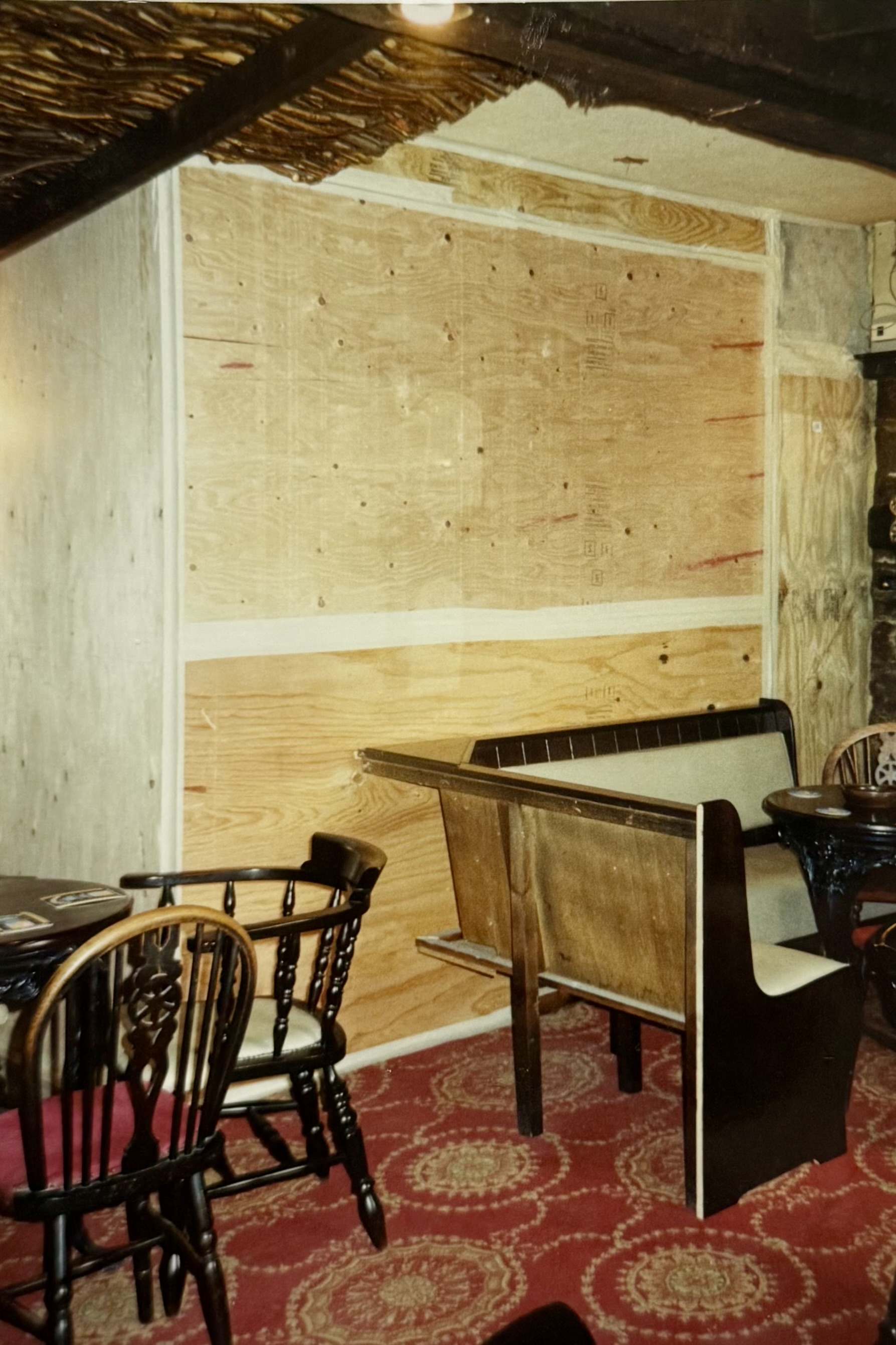 Some tables and banquet seating in front of a temporary wall. Location in the pub unclear.