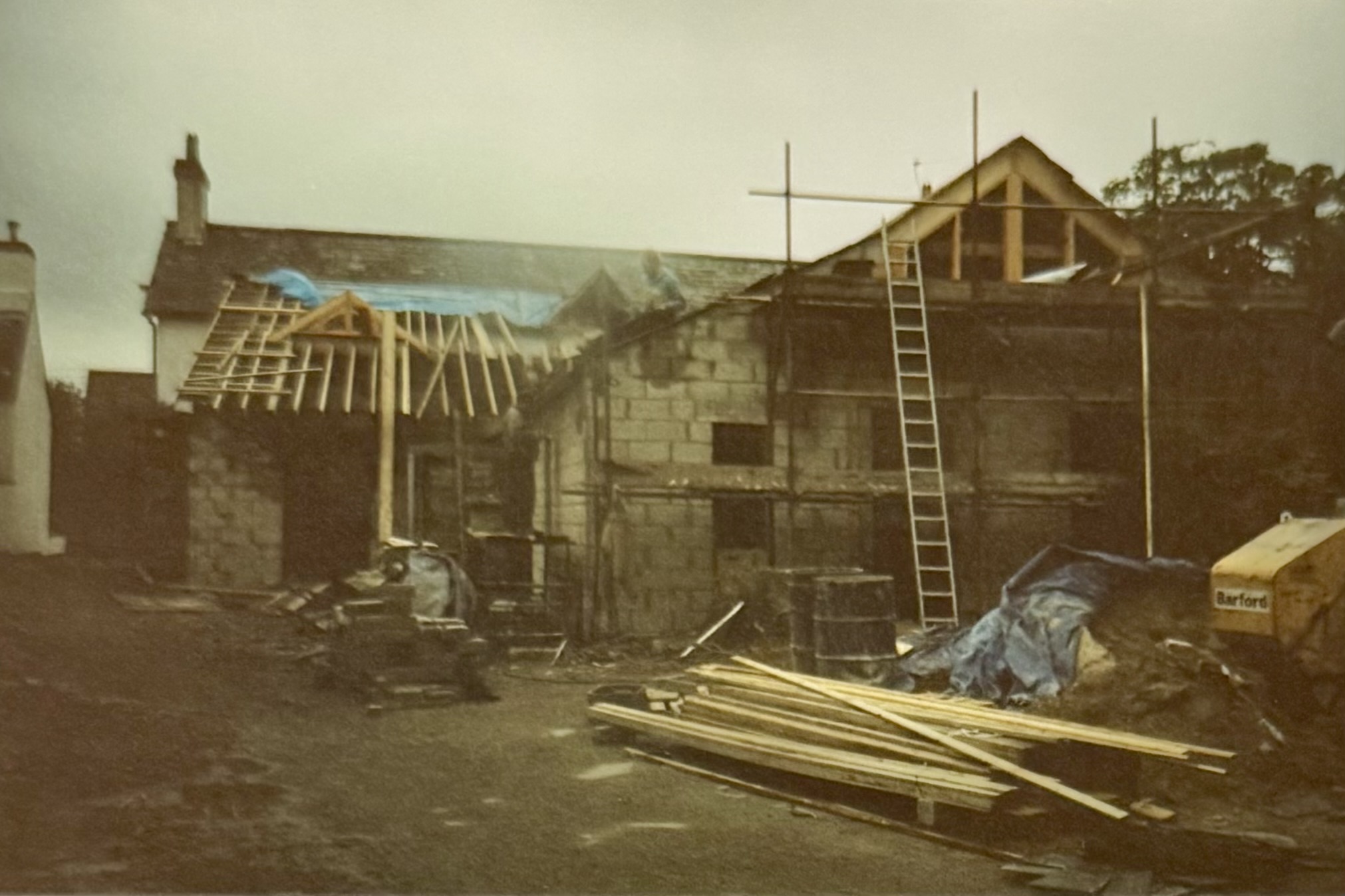 Same as above, with a man sat on the roof and a ladder leaning against the wall nearby.