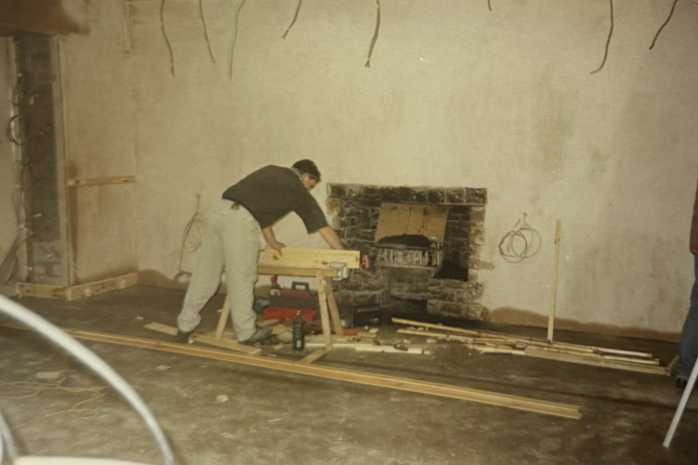 A man doing some work in what is now the Lounge area. You can see wiring hanging from the ceiling, as well as the fireplace.