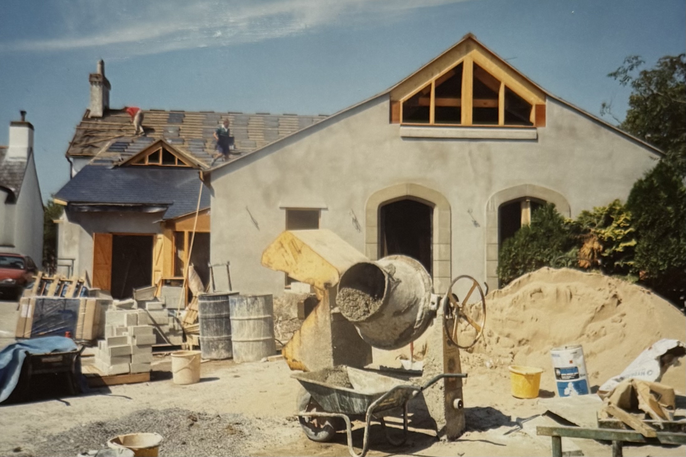 A cement mixer, and the rendered Function Room in the background. Roof tiles are being placed.