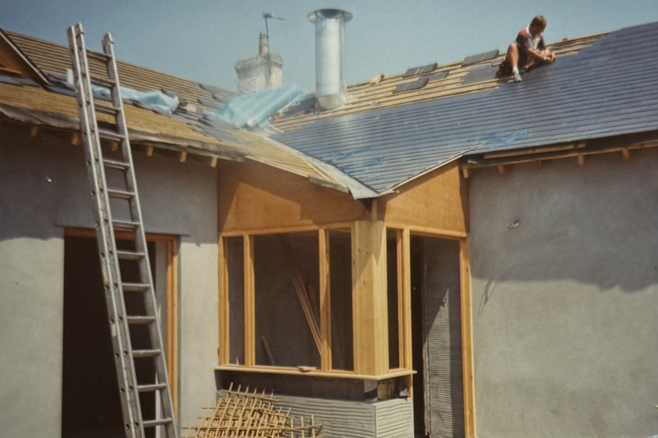 A man laying tiles on the roof above the back porch of the pub.