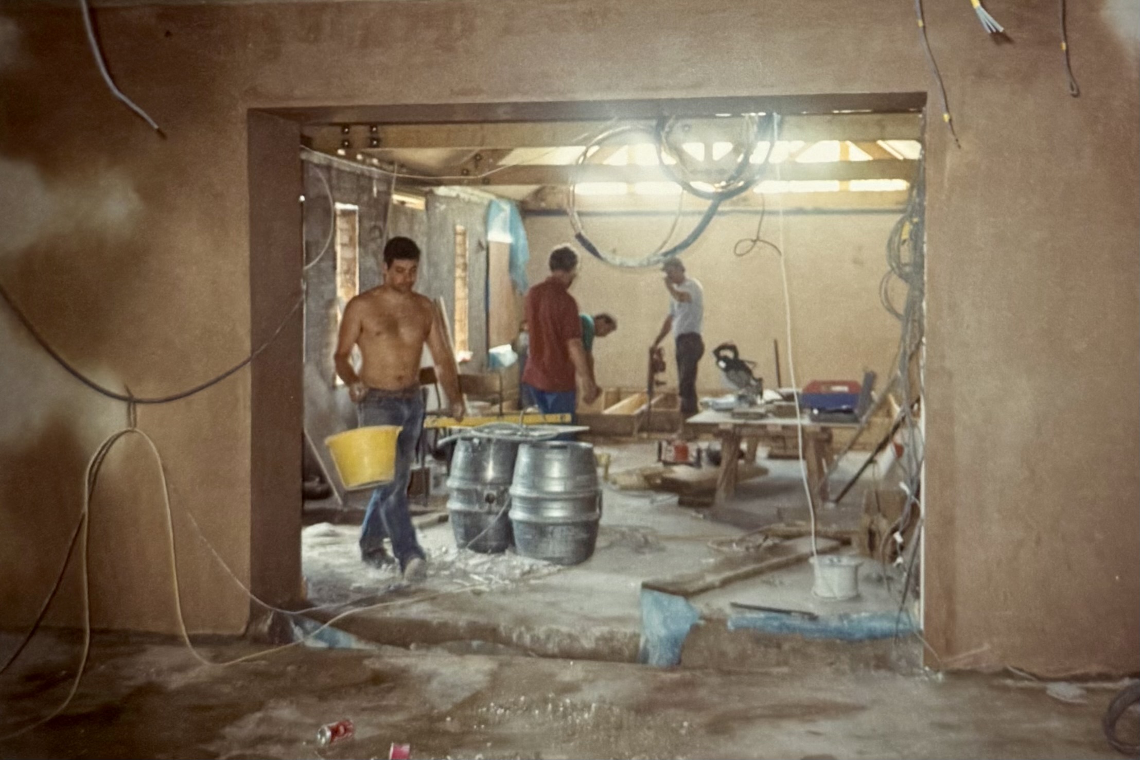 Some workmen in the Restaurant area. There's two beer barrels in the middle of the room, and wiring everywhere.