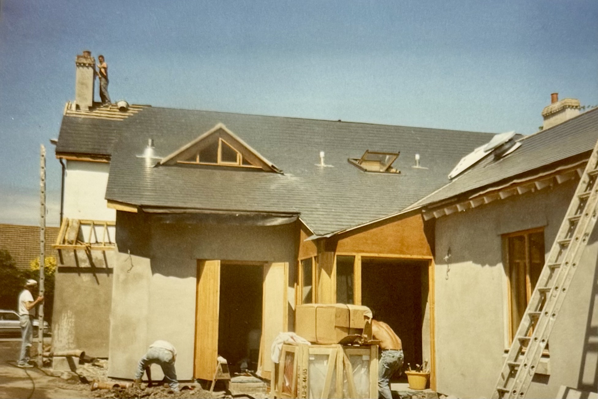 Towards the end of the renovations, the back of the pub is taking shape. There's workmen stood around, and a man on the roof next to the chimney.